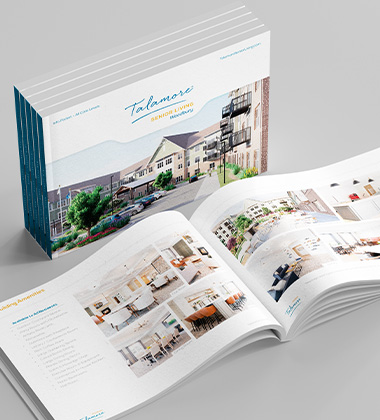 Open architectural brochure showing a residential development with a large cover image and spread-out interior photos.